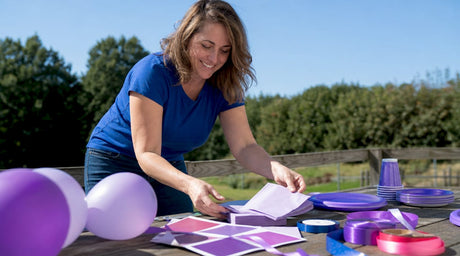 Woman arranging purple party supplies on dining table