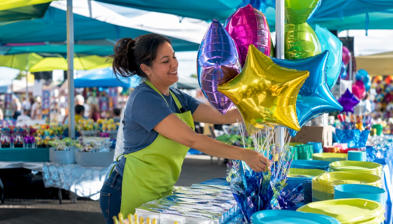 Employee arranging party supplies in store aisle