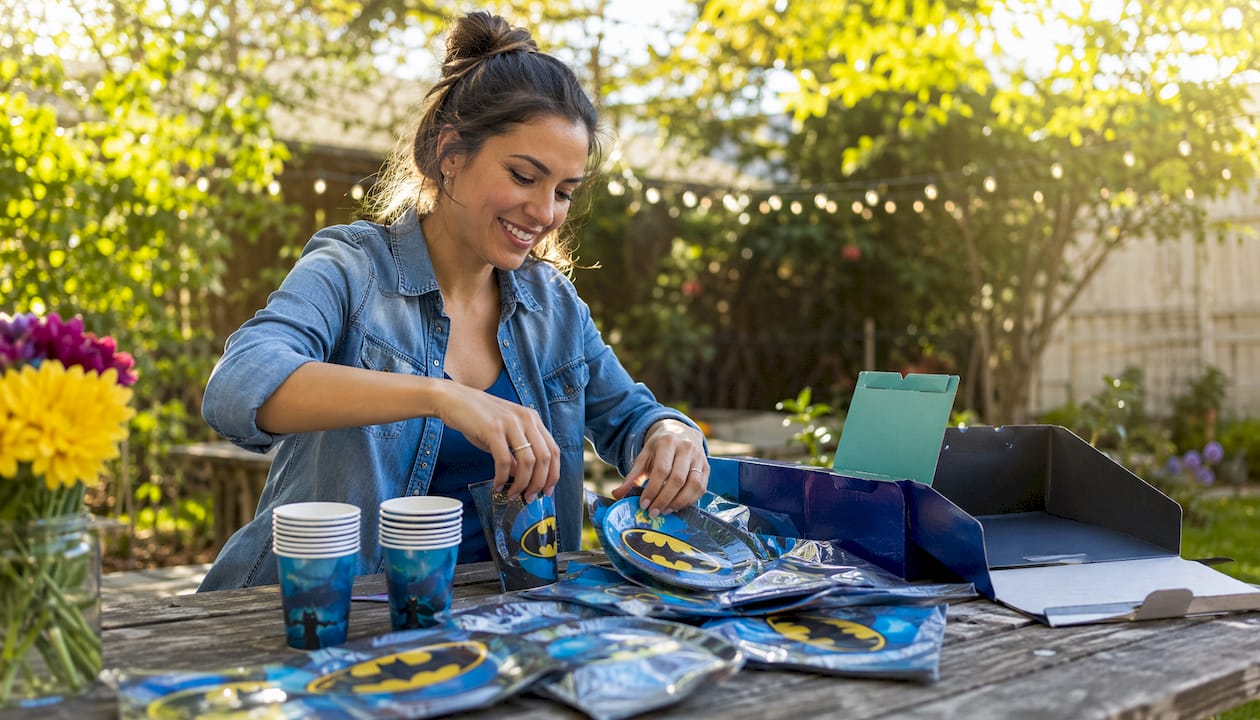 Woman unboxing Batman party supplies at table