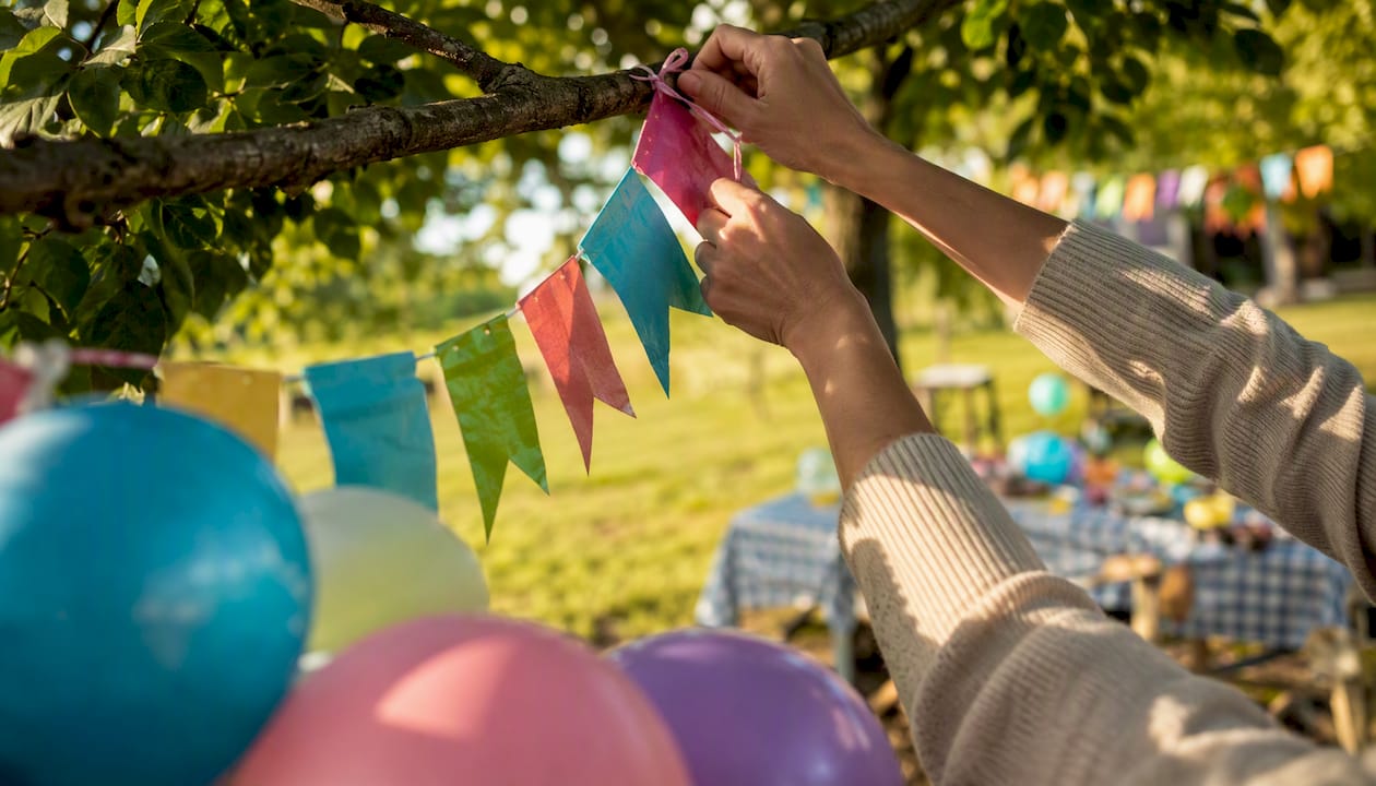 Hands tying birthday banner indoors