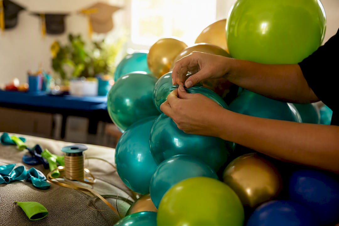 Hands assembling graduation party balloon garland