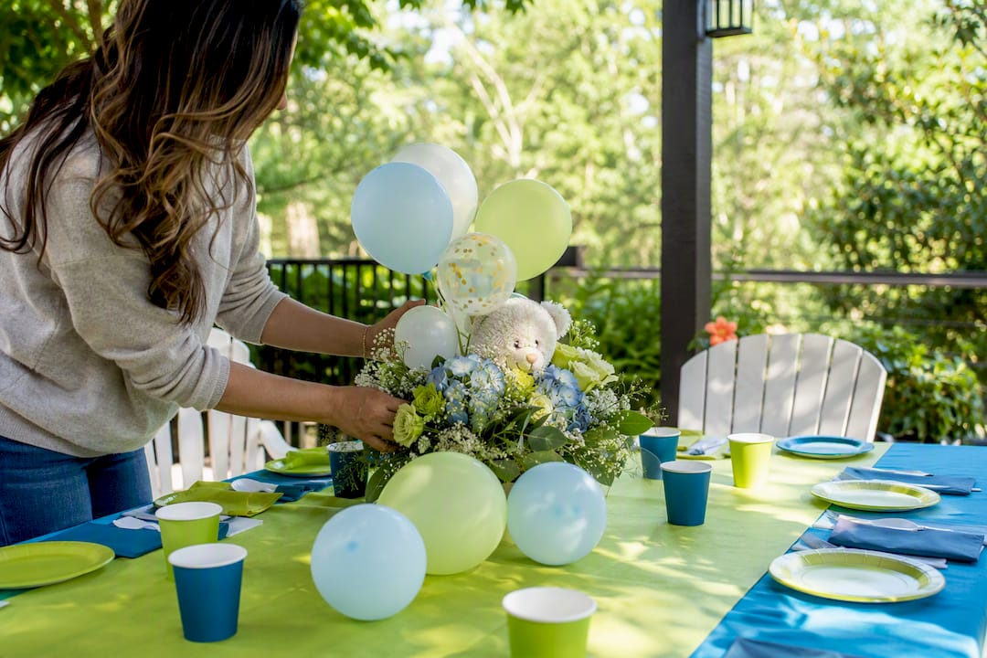 Hands assembling baby shower centerpiece with balloons