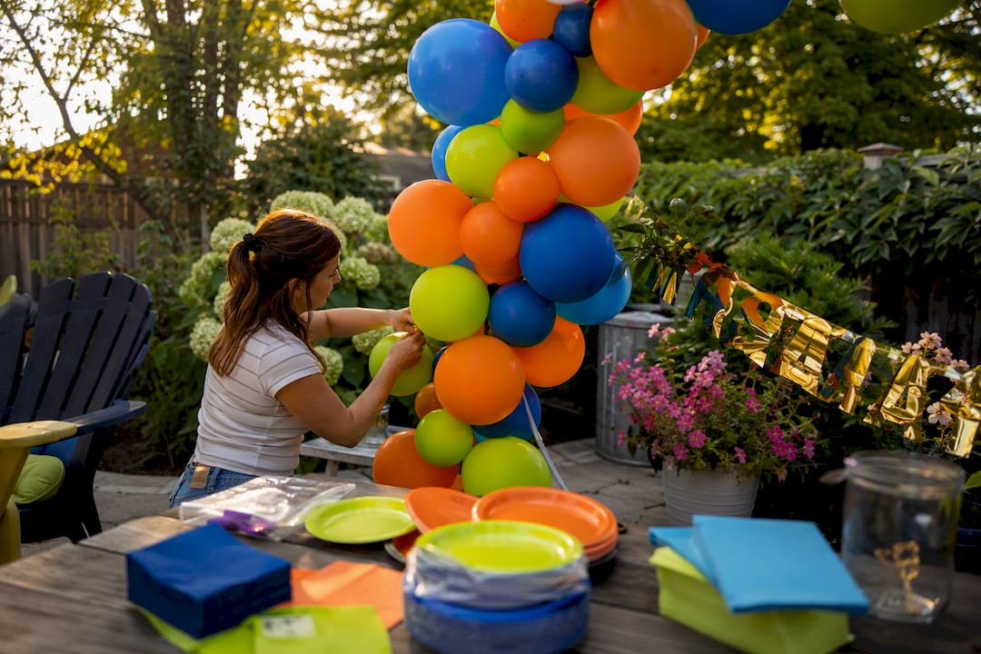 Hands assembling balloon arch with graduation banner